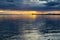 A sea pier with a lighthouse against the backdrop of the setting sun, a calm windless bay