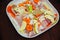 Sea raw fish with peppers, vegetables and onions with apples in a white cooking dish. Braised fish