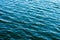 Sea ripples. Bright background. Dark green water. Shallow waves and sun glare on the water.