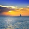 sea and sailboat over cloudy sky and sun during sunset in Cozumel, Mexico