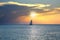 Sea and sailboat over cloudy sky and sun during sunset in Cozumel, Mexico