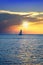 sea and sailboat over cloudy sky and sun during sunset in Cozumel, Mexico