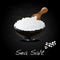 Sea salt in ceramic bowl for cooking or spa, isolated on dark background