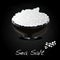Sea salt in ceramic bowl for cooking or spa, isolated on dark background