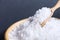 Sea salt white crystals on wooden spoon in wooden bowl isolated