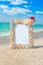 Sea shells frame with christmas hat against sea beach