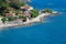 Sea shore with beach and rocks and rocky slope of the Island of Elba in Italy. Many people on the beach sunbathing. Blue sea with