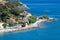 Sea shore with beach and rocks and rocky slope of the Island of Elba in Italy. Many people on the beach sunbathing. Blue sea with