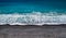 Sea shore with black sand and pebbles and breaking wave, high angle perspective