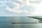 Sea shore with pier, aerial view. Sea water and cloudy sky horizon line. Summer vacation concept. Wanderlust, travel, trip. Advent