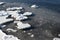 Sea shore in winter, covered with ice and snow. Round ice floes floating in sea