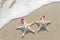 Sea-stars couple in santa hats on the sand.