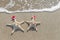 Sea-stars couple in santa hats on the sand.