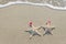 Sea-stars couple in santa hats on the sand.