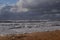 Sea storm and sea in foam, sea in barracks, sea worried and carried to shore, beach, golden sand, clouds and clouds mixed