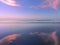 Sea at sunset with cloud reflections on sand