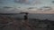 Sea sunset view. Man with backpack on rocks with beautiful view of Yeronisos Island near coast of Agios Georgios Pegeias