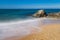 Sea surf, blurred movement of waves and foam on a sandy beach with rocks