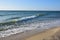 The sea surf rolls over the sandy beach in small waves