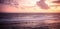 Sea surf waves on Bali beach Melasti sunset scenery with sea horizon with sunset sky with pink orange clouds with surf waves