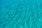 Sea surface turquoise blue color background, some reflections. Calm crystal clear water with small ripples