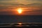 A sea view of a windfarm at sunset