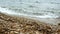 Sea water on a beach with thick sand, small waves next to a rock