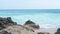 Sea water waves splashing on sandy beach landscape. Turquoise ocean on skyline landscape. Rocks on sandy beach.