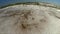 Sea wave with white foam rolls over sandy shore of beach. Top view.