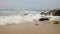 Sea waves break on the rocks on the sandy shore