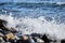 Sea waves break on shingle beach. Small wave rolls onto shore and splash of foam flies in different directions. Beautiful marine