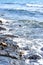Sea waves break on shingle beach. Small wave rolls onto shore and splash of foam flies in different directions. Beautiful marine