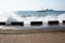 Sea waves breaking on the pier, resort embankment, sun glare on the water.