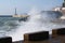 Sea waves breaking on the pier, resort embankment, sun glare on the water.