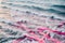 Sea waves carry dozens of floating pink ribbons