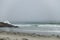 Sea waves crashing on black rocks on a foggy day