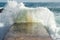 Sea waves hit the cement pier on a beach. Wild nature