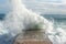 Sea waves hit the cement pier on a beach. Wild nature