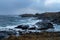 Sea with waves hitting coastline with lighthouse