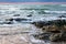 Sea waves hitting rocks on the beach with turquoise sea water causing water splashes. Amazing rock cliff seascape in the