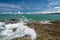 Sea waves lash line impact rock on the beach under blue sky