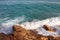 Sea waves with spray and foam crash on the rocky coast