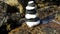 Sea waves washes the rock with black and white stones zen pyramid pile of stones