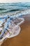 Sea waves in the white foam on the sandy beach. Dawn