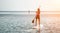 Sea woman and man on sup. Silhouette of happy young woman and man, surfing on SUP board, confident paddling through