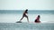 Sea woman and man sup. Silhouette of happy young woman and man, surfing on SUP board, confident paddling through water