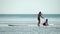 Sea woman and man sup. Silhouette of happy young woman and man, surfing on SUP board, confident paddling through water