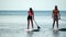 Sea woman and man sup. Silhouette of happy young woman and man, surfing on SUP board, confident paddling through water