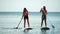 Sea woman and man sup. Silhouette of happy young woman and man, surfing on SUP board, confident paddling through water