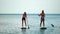 Sea woman and man sup. Silhouette of happy young woman and man, surfing on SUP board, confident paddling through water